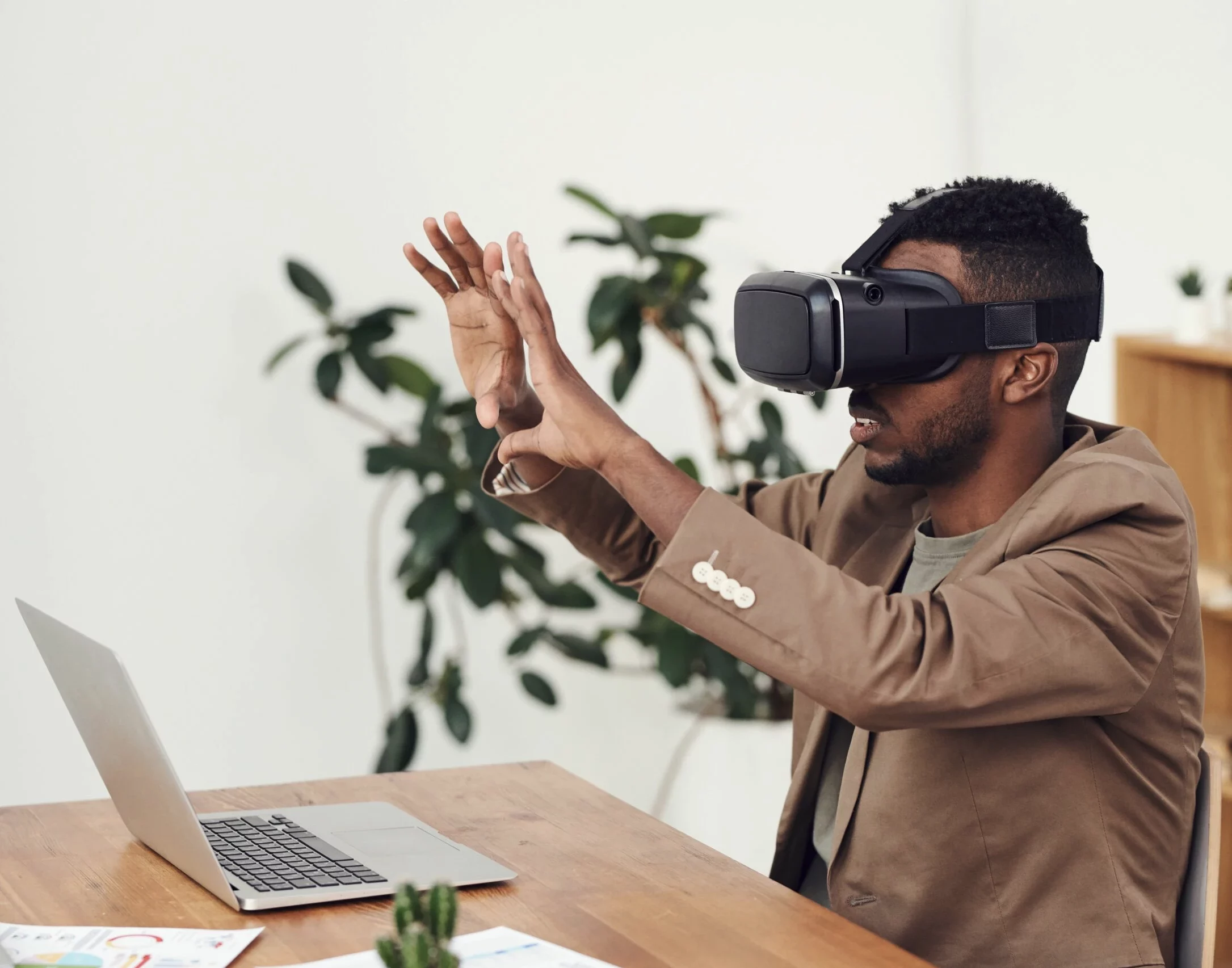 Black man holding a VR set in front of his laptop